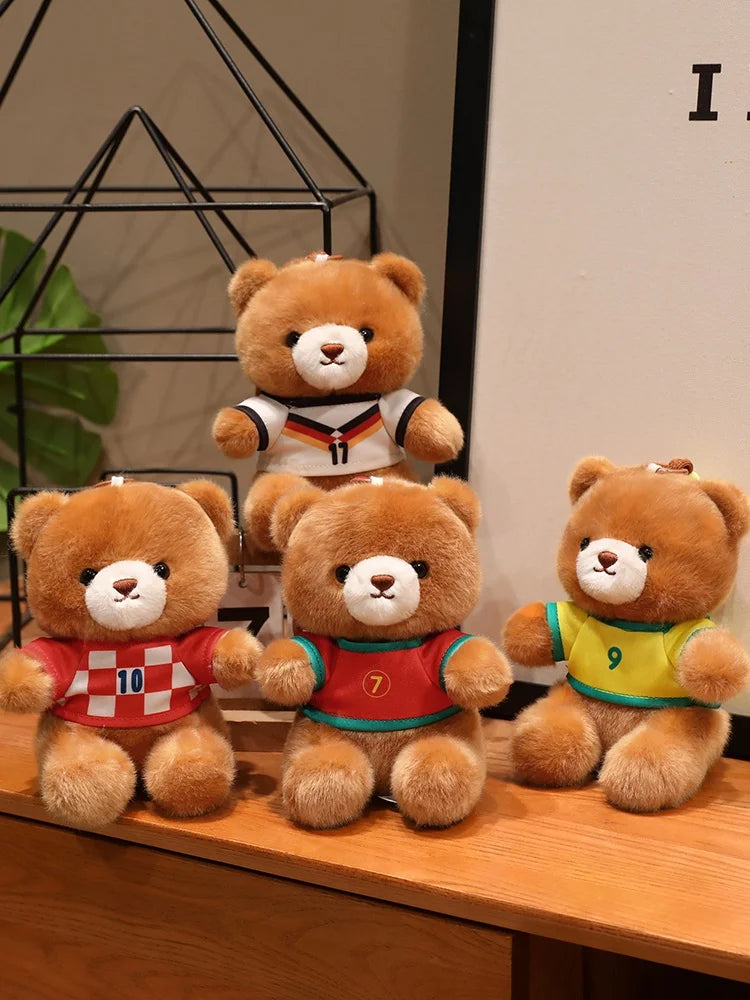 Three adorable teddy bears wearing football jerseys numbered 10, 7, and 9 sitting on a wooden surface.