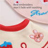 A close-up of a pink baby bib with embroidery and a yellow shirt featuring a cute animal design.