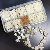 A clear plastic box holds various white acrylic pearl bead mixes for jewelry making, with loose beads displayed below.