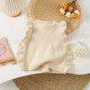 A beige knit sweater vest for girls with a flower shape and ruffled edges, displayed on a white surface.