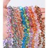 Eine Hand hält mehrere Fäden aus farbigen facettierten Glasperlen in Violett-, Blau-, Pink- und Bernstein-Tönen.