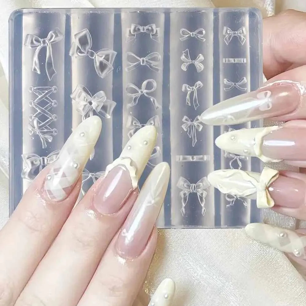 A hand displays silicone nail molds featuring various bowknot designs and a carving pen on a clear background.