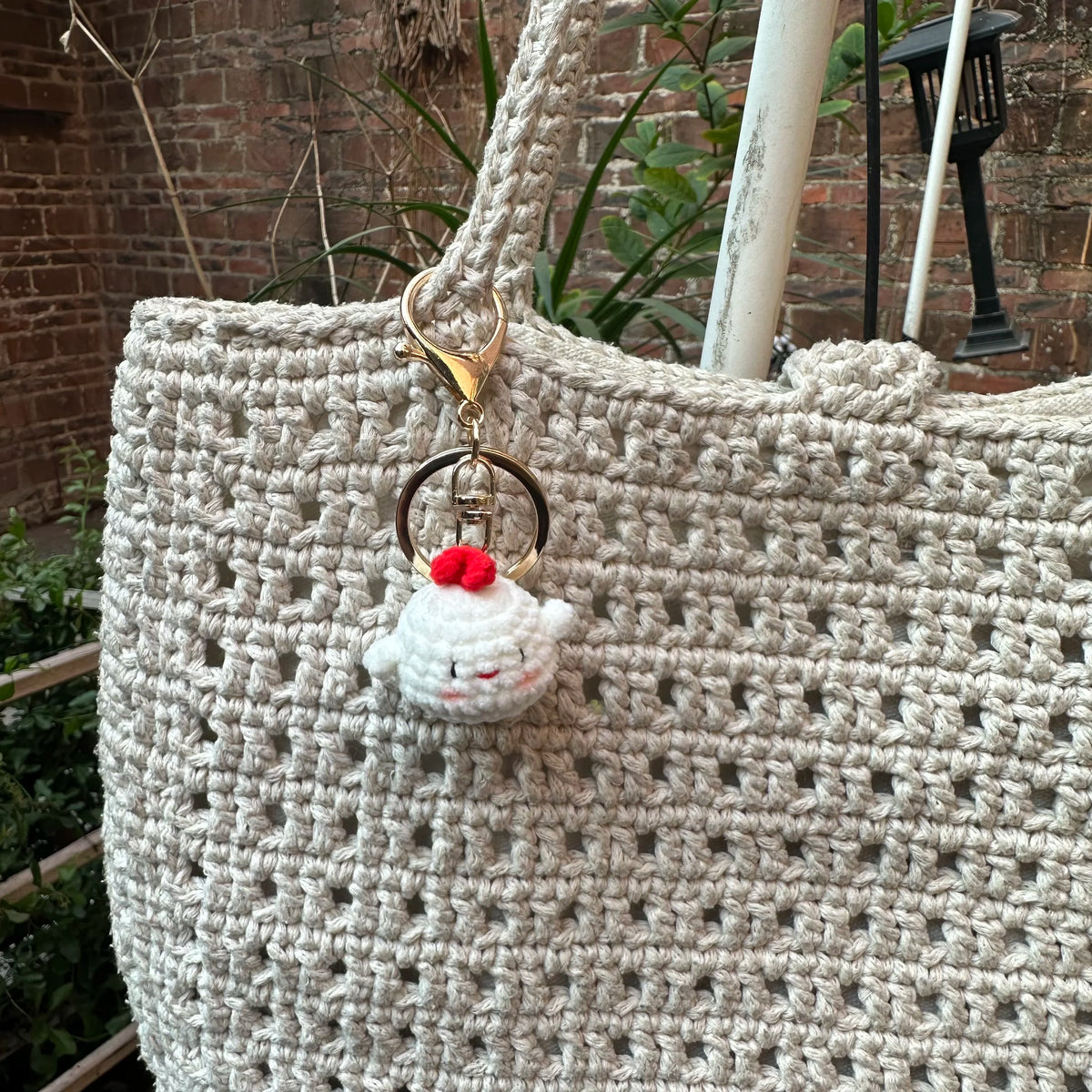 A handcrafted crochet animal keychain featuring a white rabbit or chick charm attached to a gold-toned ring.