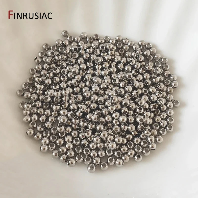 A pile of small, round, silver-colored spacer beads for jewelry making.