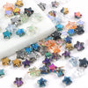 A collection of iridescent and colored glass star spacer beads for jewelry making displayed on a white surface.