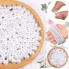 A pile of small, round ivory pearl beads arranged on a wooden surface.