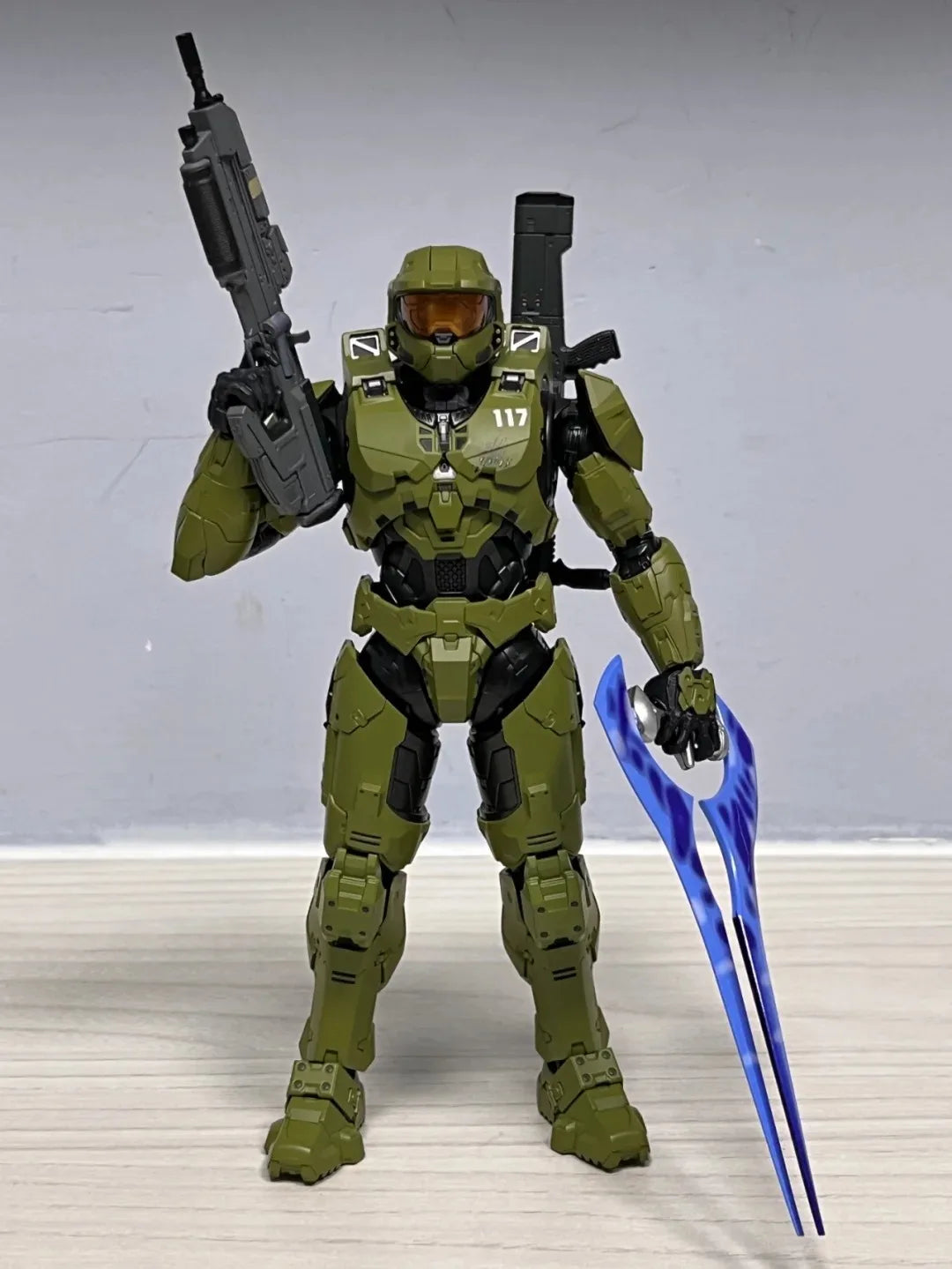 A 1/12 scale Master Chief action figure in olive green armor holding a rifle and a blue blade.