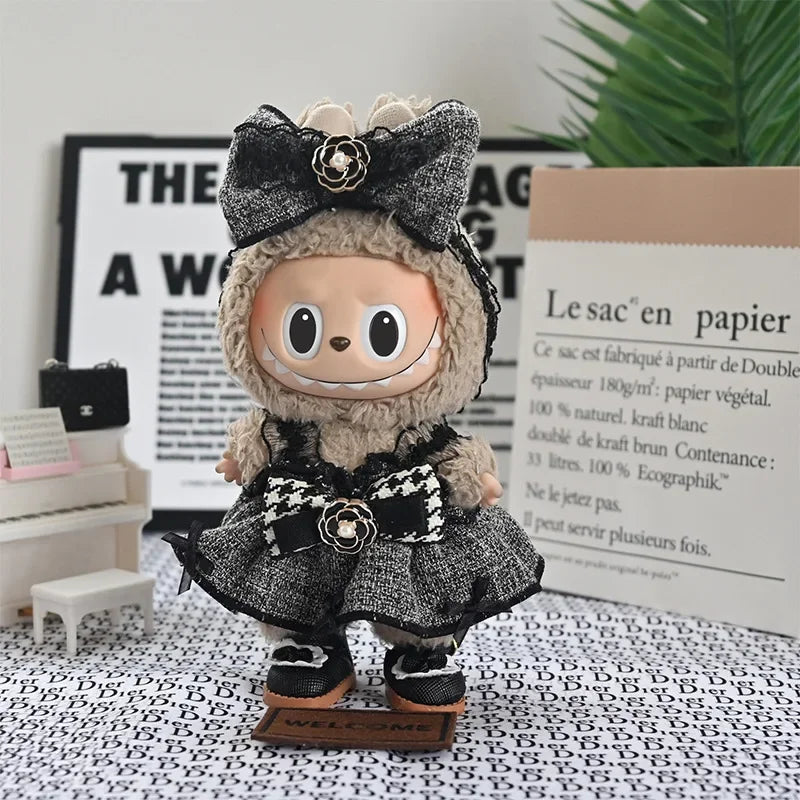 A plush Labubu doll wearing a black and gray flannel outfit with a bow and a flower, displayed in front of a sign.