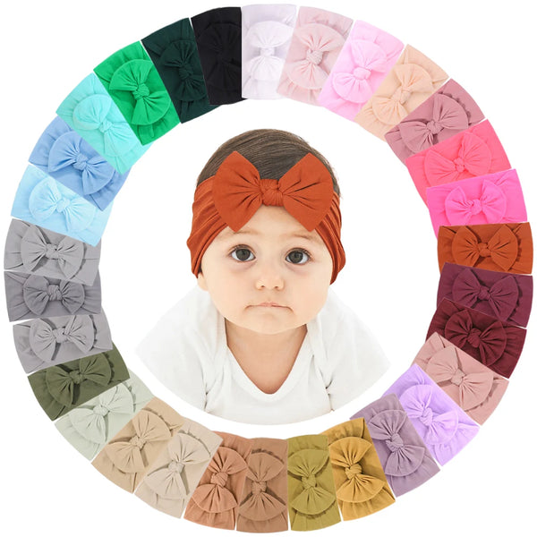 A circular arrangement of various pink, purple, green, and brown nylon knit bow headbands for baby girls.