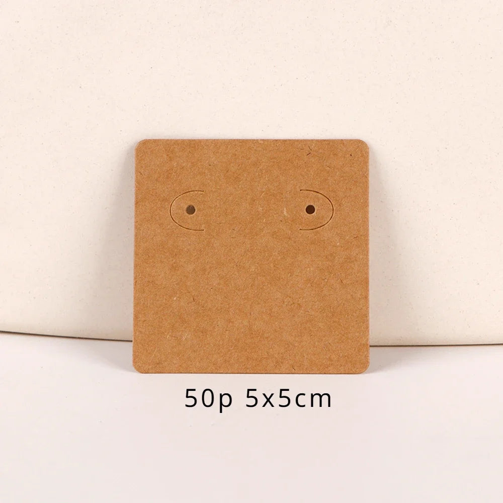 A square brown kraft card with two small circular holes for jewelry display, shown on a white background.