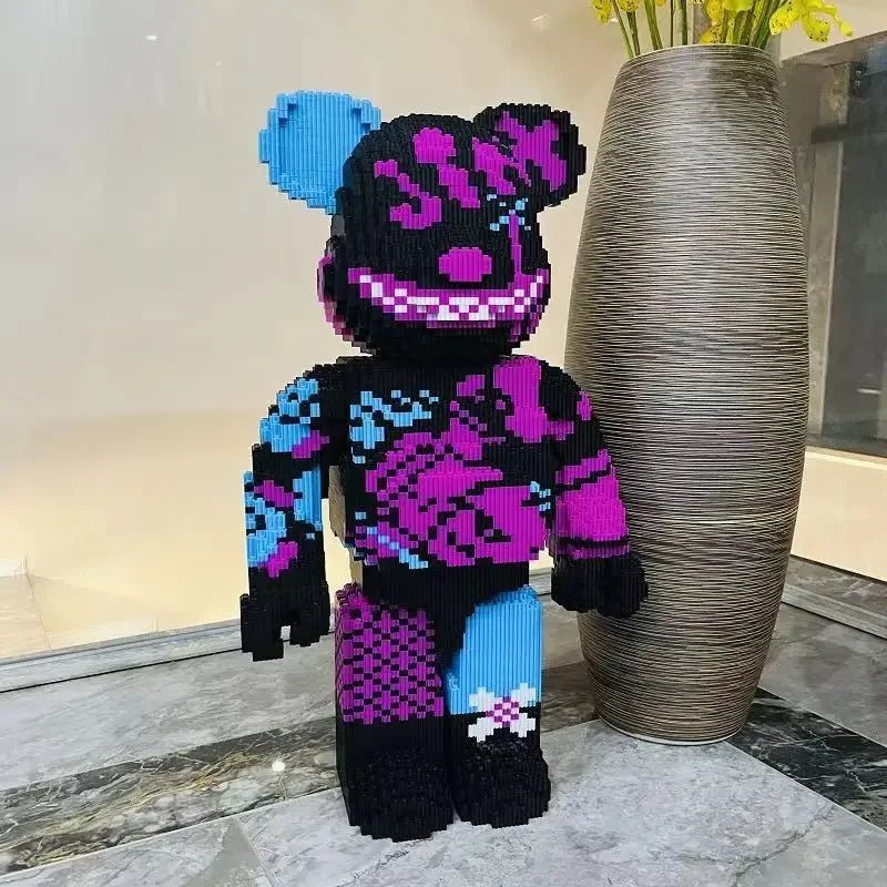 A large, black knitted bear building block model with purple and blue accents displayed next to a tall vase.