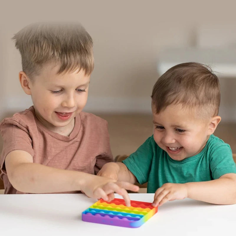 Deux jeunes enfants jouent avec un jouet coloré servant d'outil anti-stress pour les lettres et les chiffres.
