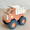 A plastic pull-along bulldozer toy truck with an orange cab and a white dump bed on a light background.