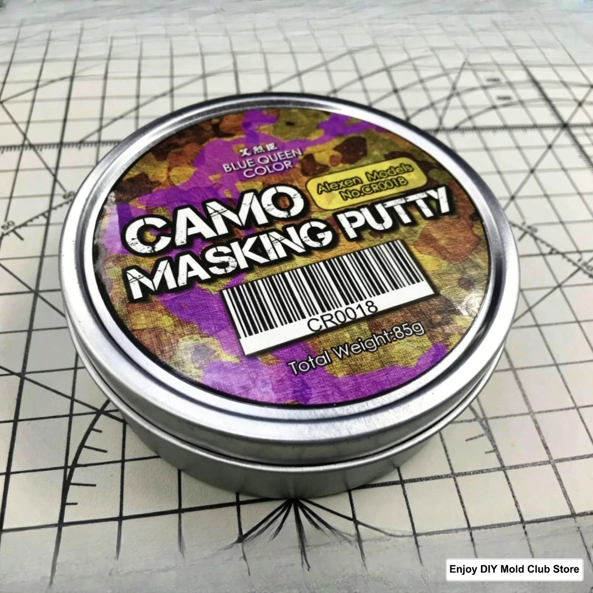 A tin of Camo Masking Putty for model painting with a barcode and weight label on a grid background.
