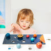 A child points at a wooden solar system puzzle featuring eight planets and the sun.