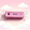 A pink squishy fidget toy shaped like a grape is packaged in clear plastic against a light pink background.