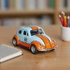 A 1:36 scale die-cast retro Beetle car painted light blue and orange sits on a wooden table.