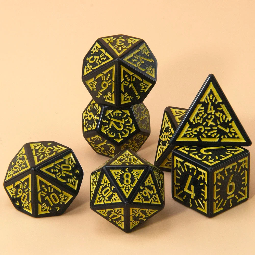 A set of seven polyhedral dice in black and yellow are displayed on a light brown surface.