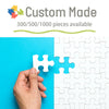 A hand is assembling a white jigsaw puzzle piece onto a blue background, with the text Custom Made visible above.