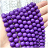 A hand holds a string of small purple natural stone beads for DIY jewelry making