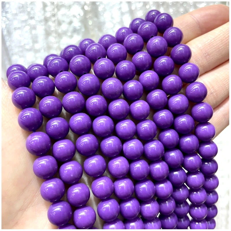 A hand holds a string of small purple natural stone beads for DIY jewelry making