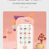 A pink baby phone toy with various buttons and a heart shape is displayed on a wooden surface.