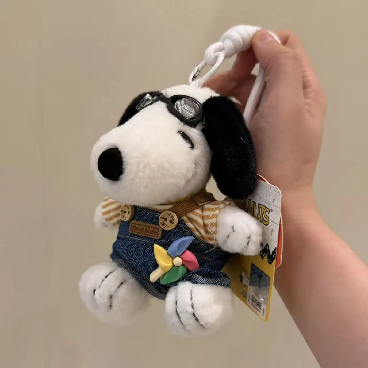 A white dog plush toy with black ears and sunglasses is being held, attached to a keychain.