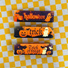 Three Halloween themed butter squishy toys featuring pumpkins and ghosts on a yellow checkered background.
