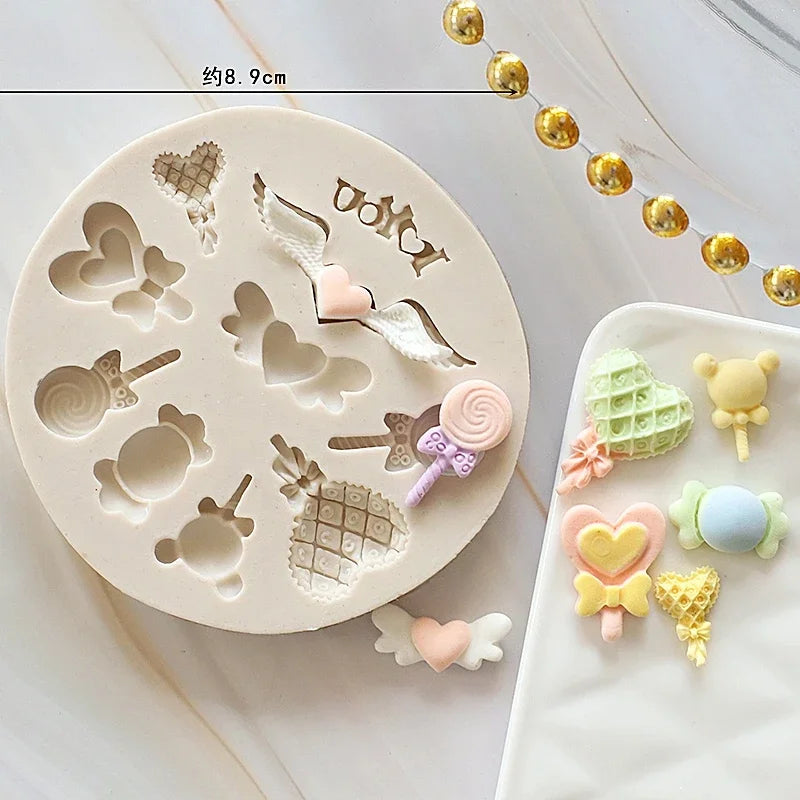 A set of silicone cake molds featuring various baby-themed shapes like hearts, pacifiers, and strollers on a white surface.