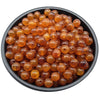 A pile of small, round, amber-colored acrylic beads for jewelry making.