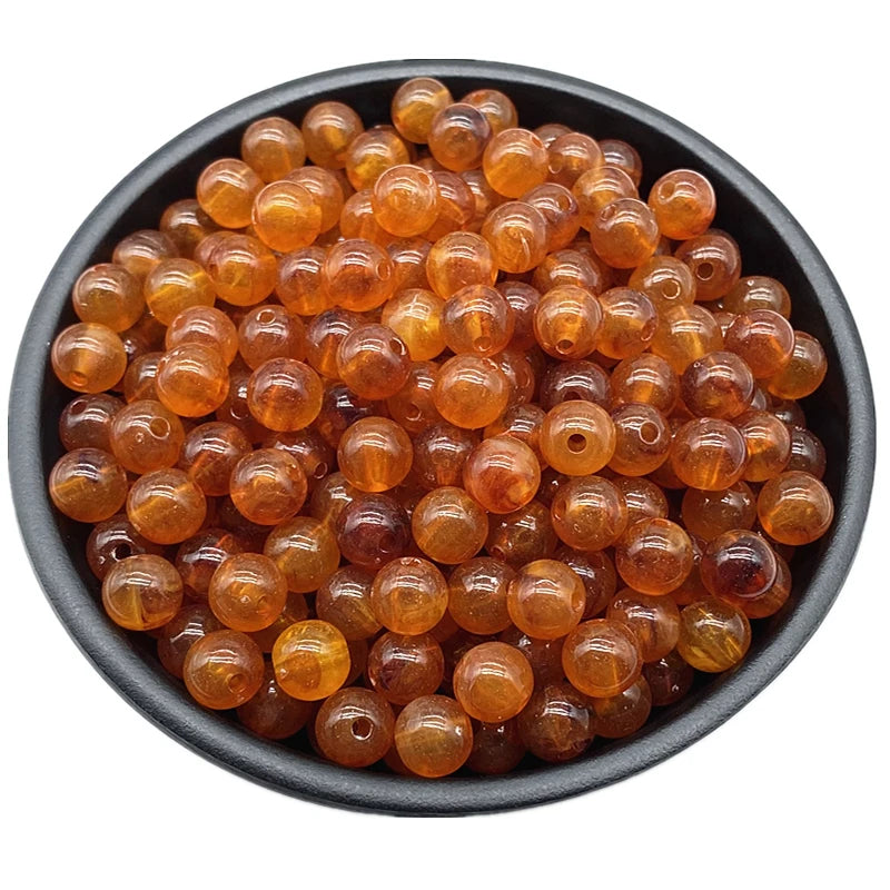 A pile of small, round, amber-colored acrylic beads for jewelry making.