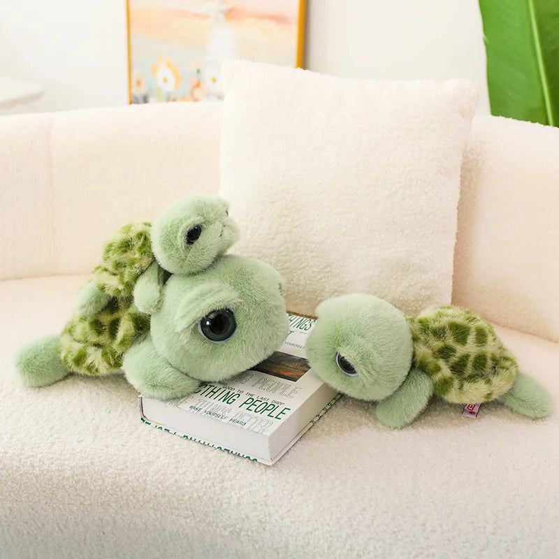 A soft green and yellow patterned tortoise plush pillow resting on a white sofa cushion.