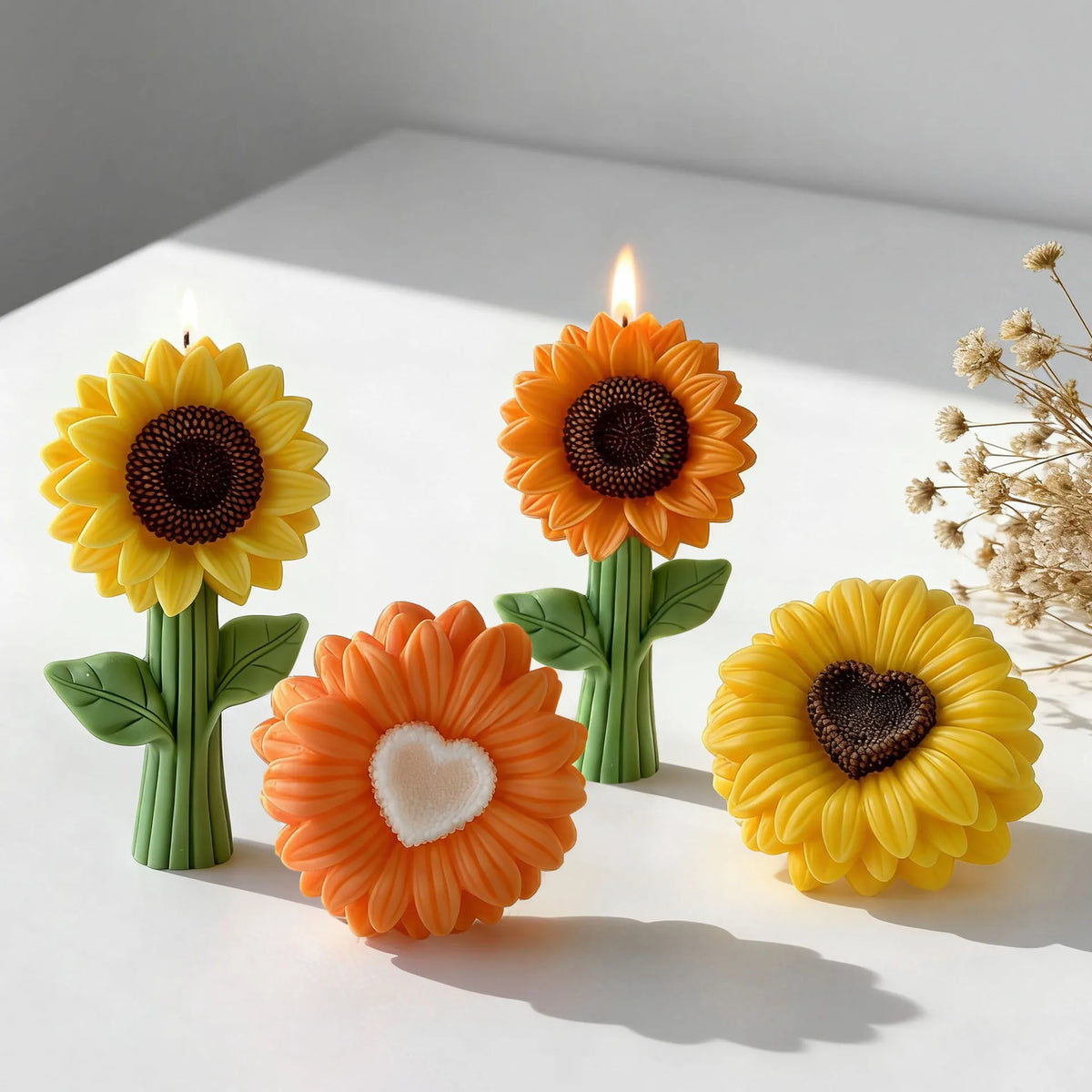 Three orange and yellow silicone sunflower molds with lit candles on a white surface.