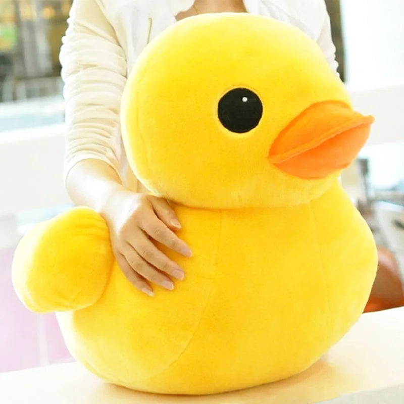 A person is holding a bright yellow plush toy shaped like a duck.