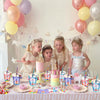 Four young girls celebrating with pink and yellow balloons and birthday party goodie bags