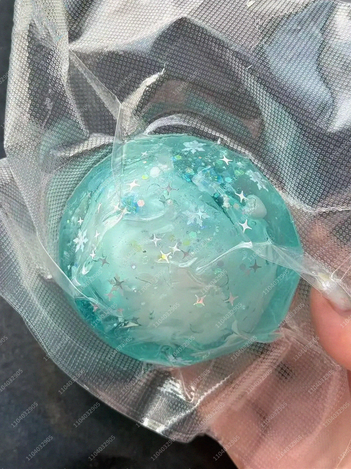 A translucent teal stress ball with glitter and stars is visible inside a clear plastic bag.