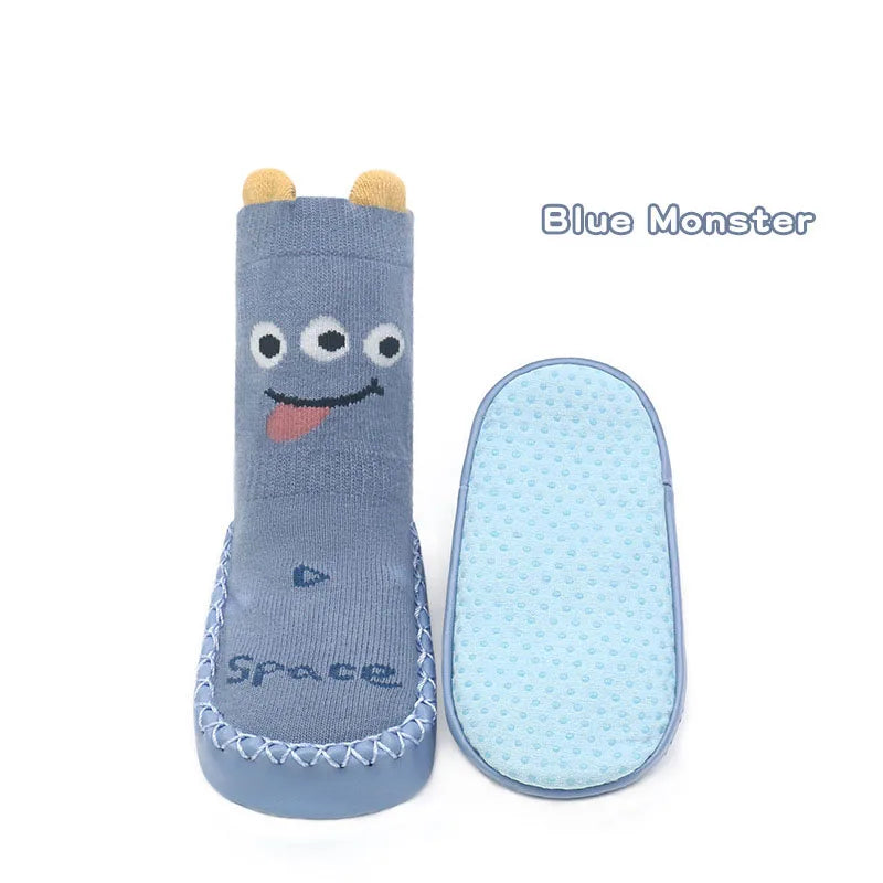 A pair of blue monster non-slip socks with cute cartoon faces and a matching light blue silicone sole.
