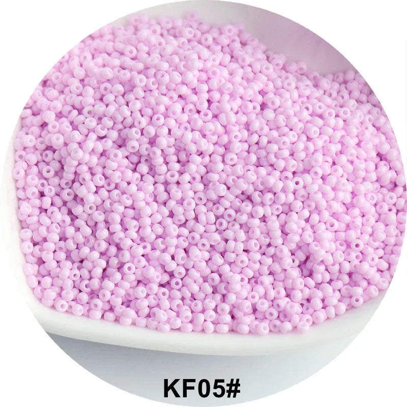 A pile of pink glass seed beads in a white dish.