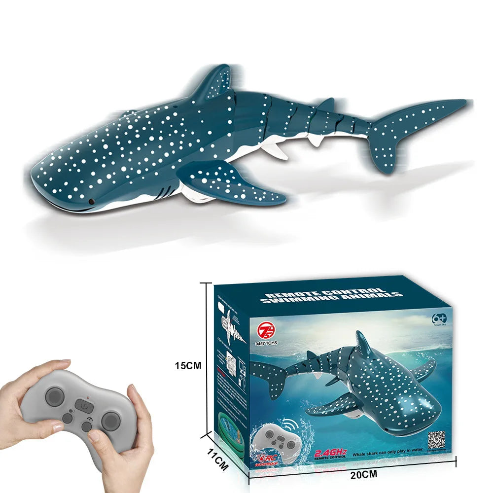A remote control shark toy is shown next to its packaging box and a hand holding the controller.