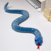 A blue and green lifelike simulation snake plush toy coiled on a white surface.