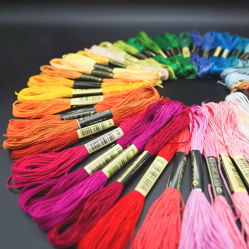 A colorful assortment of vibrant organic cotton embroidery floss in various shades of orange, pink, red, and green.