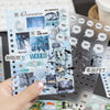 A hand holds a sheet of Kawaii K-pop sticker and photocard sheets featuring various text and illustrations for crafting.