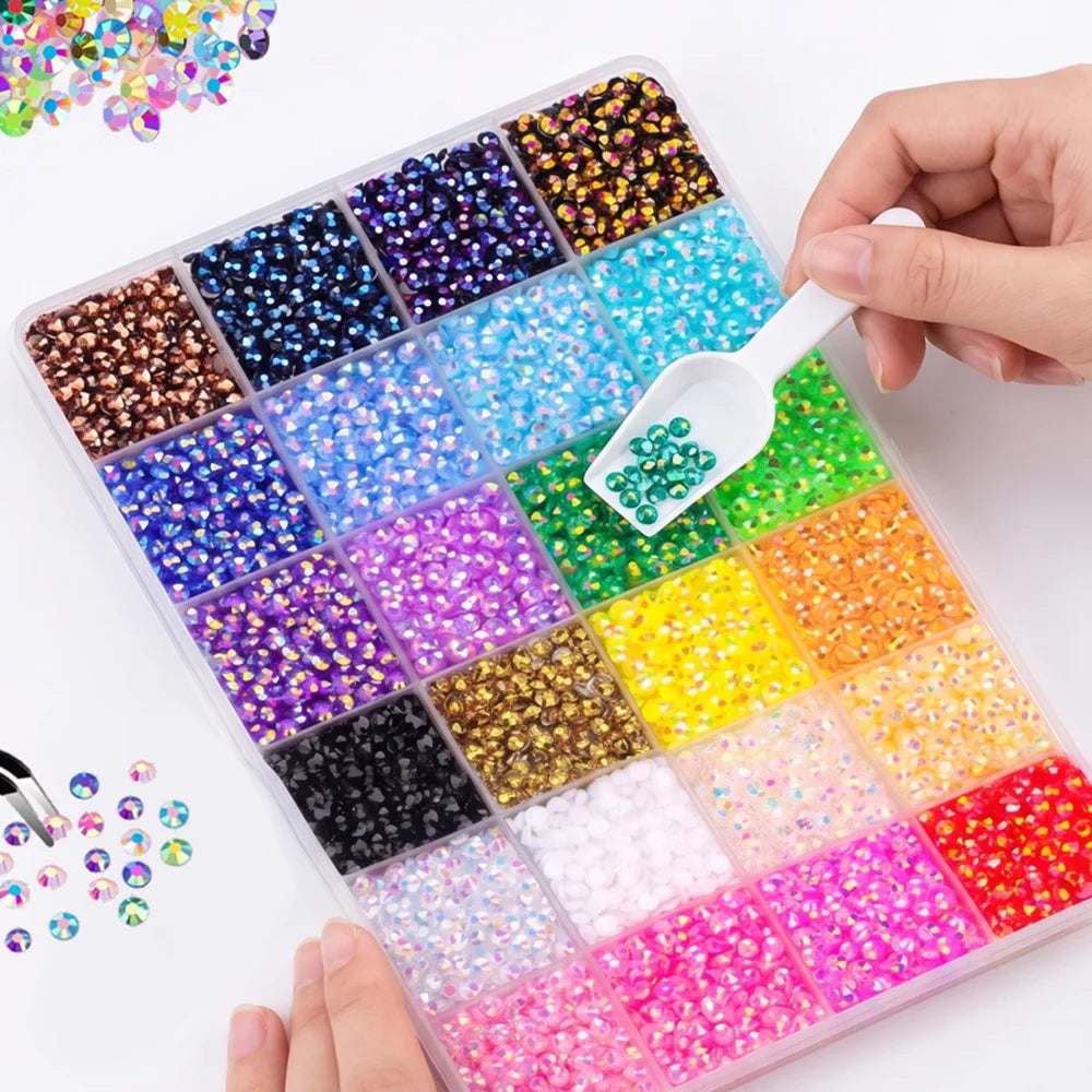 A hand is holding a clear plastic tray filled with various colors of flat-back rhinestones for DIY crafts.