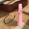 A pink portable kazoo flute with a star-shaped button and black lanyard rests on a piece of paper.