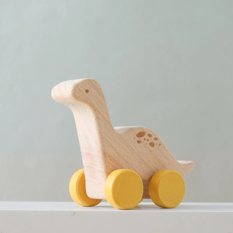 A wooden dinosaur toy car with yellow wheels sitting on a white surface.