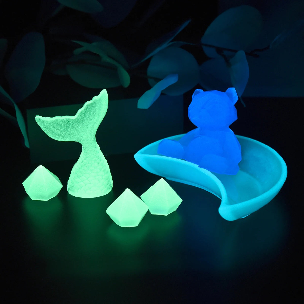 A glowing blue silicone mold of a pig and several small, glowing green pigment powder pieces on a dark surface.