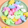 A variety of colorful mochi squishy dinosaur fidget toys are arranged on a light green plate.