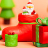 A festive arrangement of red boots, green Christmas trees, and wrapped gifts made from polymer clay.