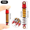 A close-up view of a red aluminum shock absorber with an orange coil spring and gold-colored mounting hardware.