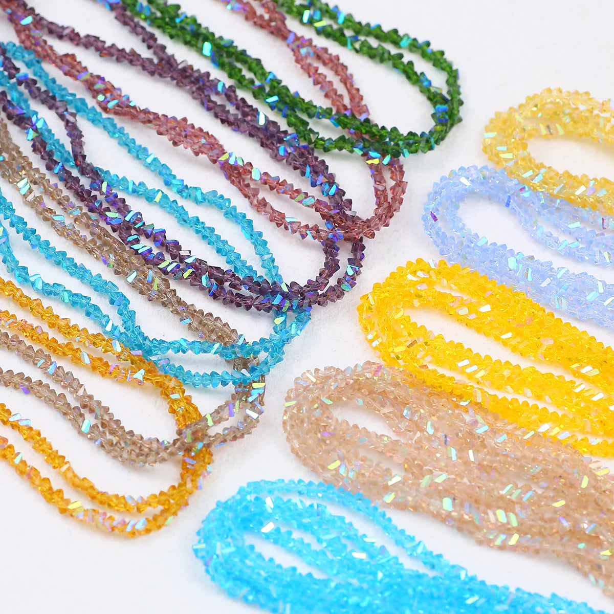A collection of colorful 3mm crystal triangle beads in various shades of blue, green, purple, and yellow laid out for jewelry